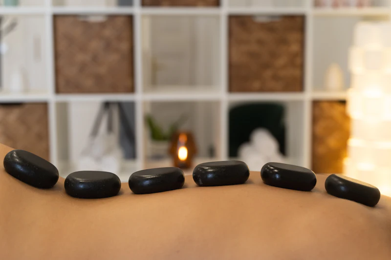 Warme massagestenen op een rug, met kaarsen op de achtergrond